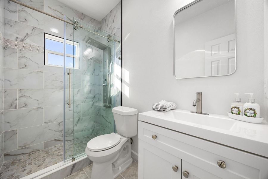 Experience luxury in this modern bathroom, which features a glass shower, marble tiles, and a sleek vanity with generous storage space. Experience luxury in this modern bathroom, which features a glass shower, marble tiles, and a sleek vanity with generous storage space.