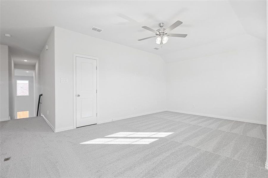 Carpeted empty room with ceiling fan and lofted ceiling