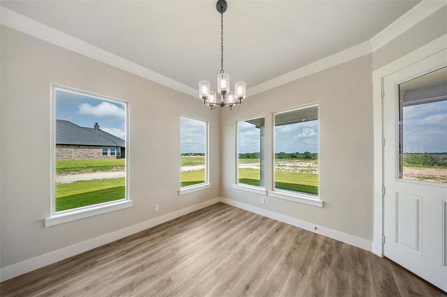 Unfurnished dining area featuring crown molding, a chandelier, and light wood-style flooring Unfurnished dining area featuring crown molding, a chandelier, and light wood-style flooring