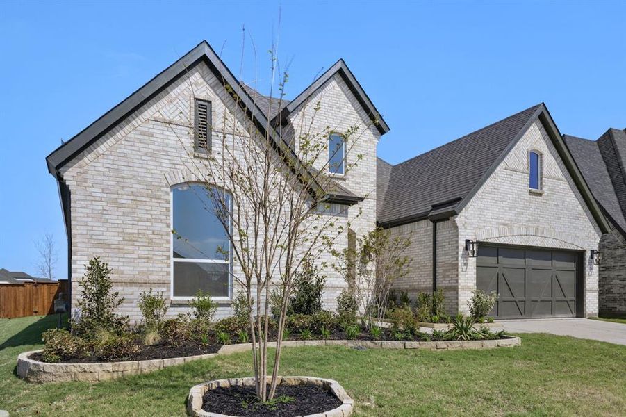 French country home with brick siding, a garage, and concrete driveway