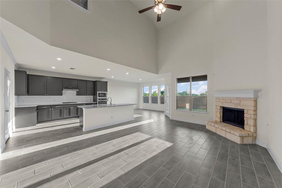 Unfurnished living room featuring wood tiled floors, high vaulted ceiling, a ceiling fan, a stone fireplace, and recessed lighting Unfurnished living room featuring wood tiled floors, high vaulted ceiling, a ceiling fan, a stone fireplace, and recessed lighting