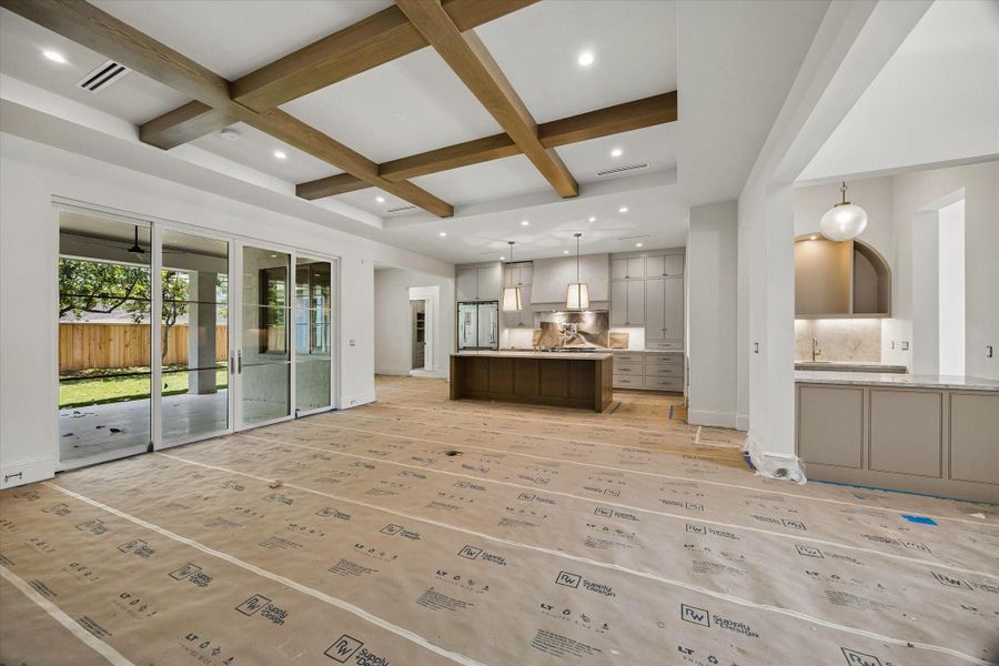 A seamless view into the kitchen, wet bar, and outdoor living area highlights the home’s effortless flow, perfect for everyday family living and entertaining. Stunning white oak beams complete the space.