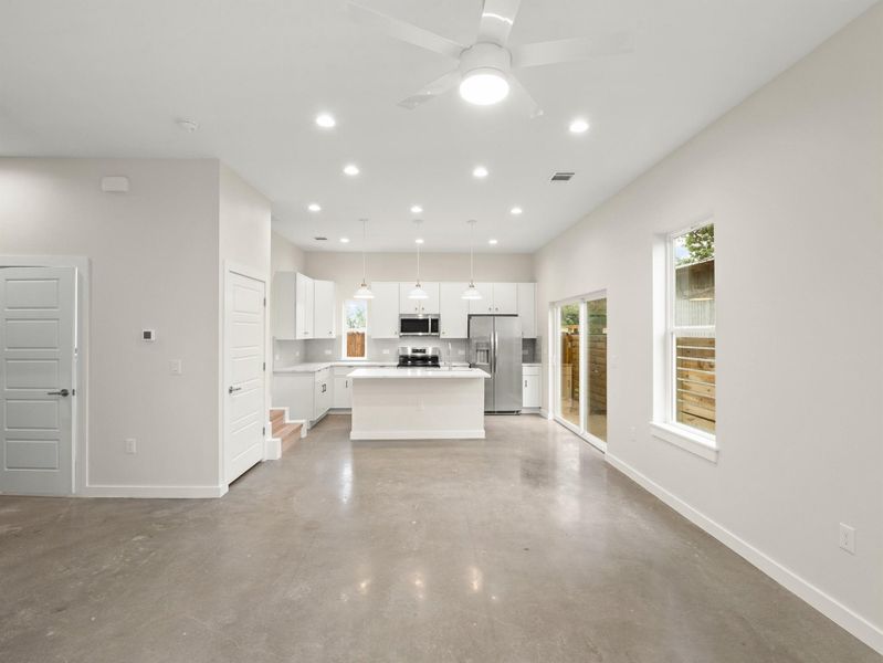 Open-concept living space featuring polished concrete flooring, recessed lighting, and a ceiling fan