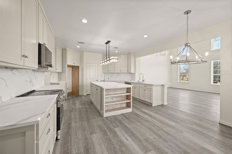 Kitchen with appliances with stainless steel finishes, a peninsula, a chandelier, open shelves, and recessed lighting Kitchen with appliances with stainless steel finishes, a peninsula, a chandelier, open shelves, and recessed lighting