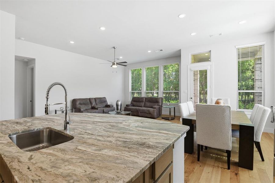Kitchen island featuring a stainless steel sink with a high-arch faucet, granite countertop, and light wood cabinetry Kitchen island featuring a stainless steel sink with a high-arch faucet, granite countertop, and light wood cabinetry