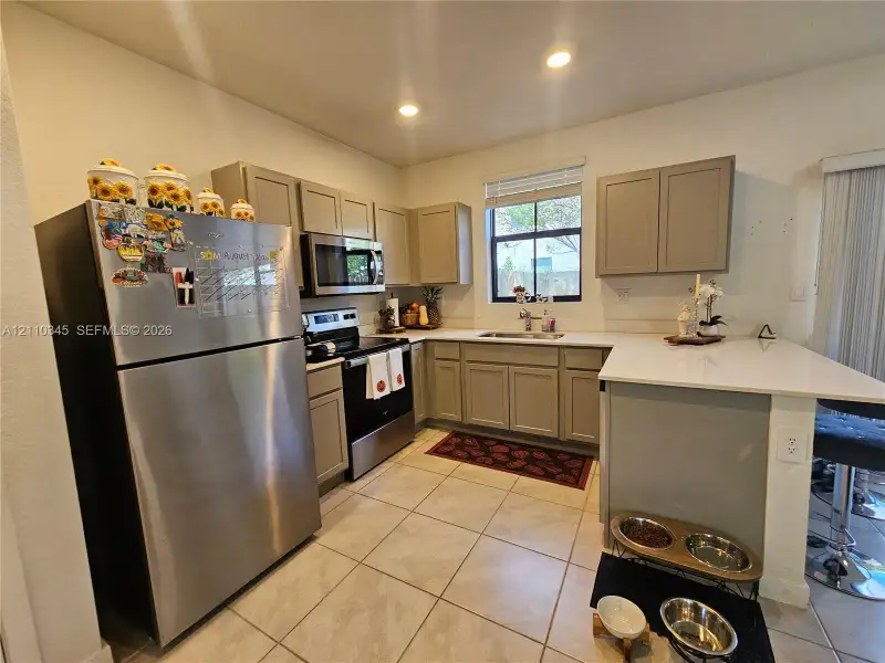 Kitchen featuring shaker-style cabinetry, solid-surface countertops, recessed lighting, tile flooring, and stainless steel appliances