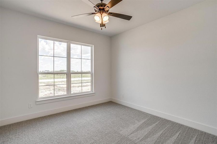 Carpeted empty room featuring ceiling fan