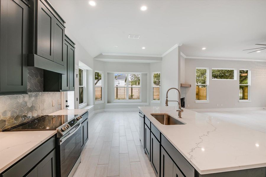 Kitchen featuring a sink, open floor plan, appliances with stainless steel finishes, light stone countertops, and tasteful backsplash