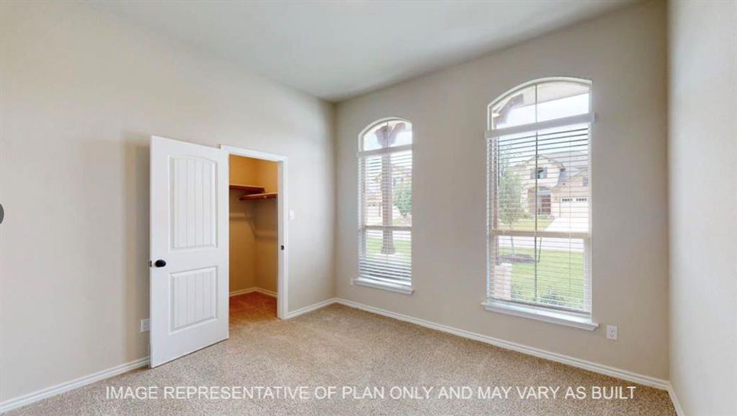 Unfurnished bedroom featuring light carpet and a walk in closet Unfurnished bedroom featuring light carpet and a walk in closet