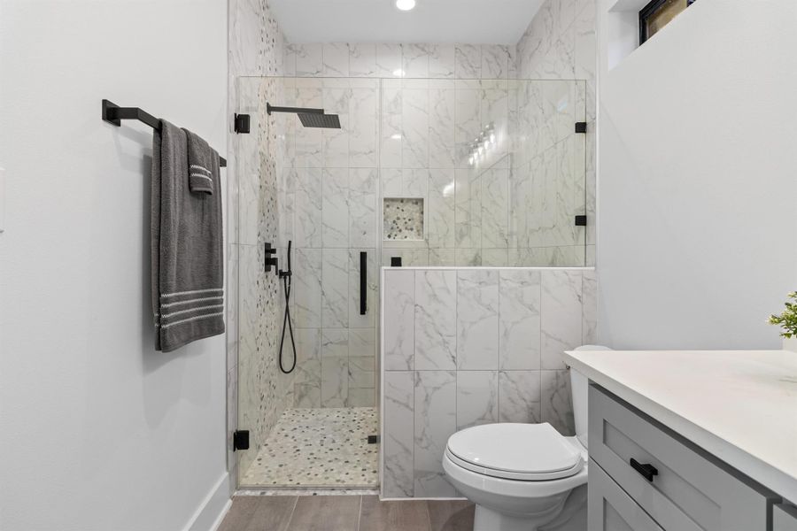 Bathroom featuring vanity, a marble finish shower, wood finished floors, and recessed lighting