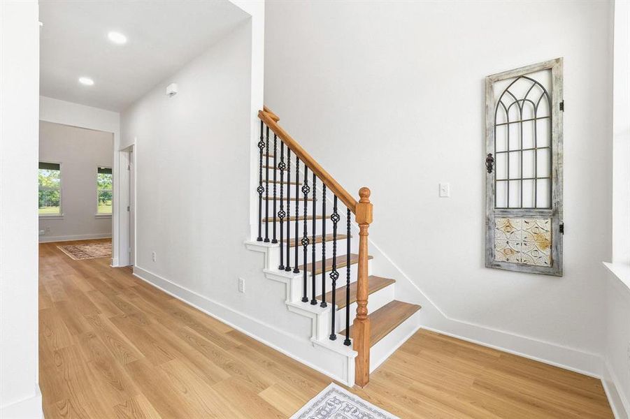 Staircase featuring wood-finish treads, white risers, and wrought iron balusters with a wood handrail Staircase featuring wood-finish treads, white risers, and wrought iron balusters with a wood handrail