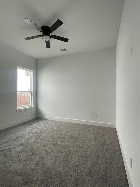 Empty room with ceiling fan and dark carpet