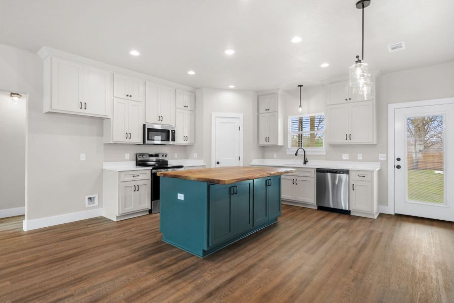 Dual tone kitchen featuring wooden counters, stainless steel appliances, dual tone cabinetry, dark wood-type flooring, and a kitchen island