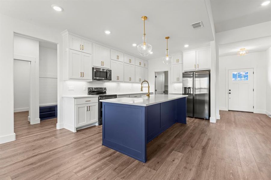 Kitchen with appliances with stainless steel finishes, light countertops, light wood-style flooring, white cabinets, and recessed lighting