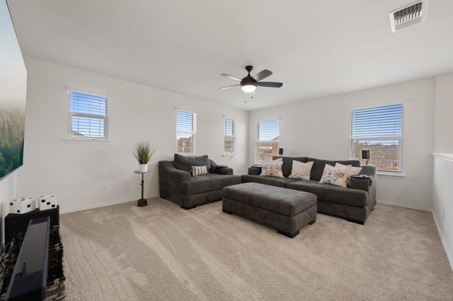 Living room featuring a ceiling fan, light colored carpet, and healthy amount of natural light