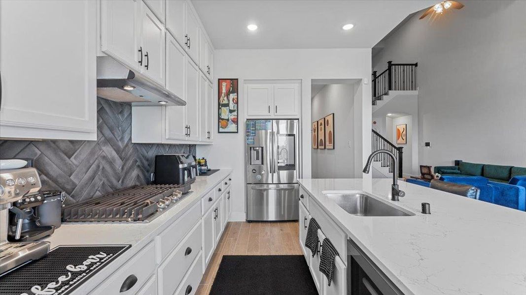 Kitchen with stainless steel appliances, light wood-style floors, white cabinetry, light stone counters, and open floor plan Kitchen with stainless steel appliances, light wood-style floors, white cabinetry, light stone counters, and open floor plan