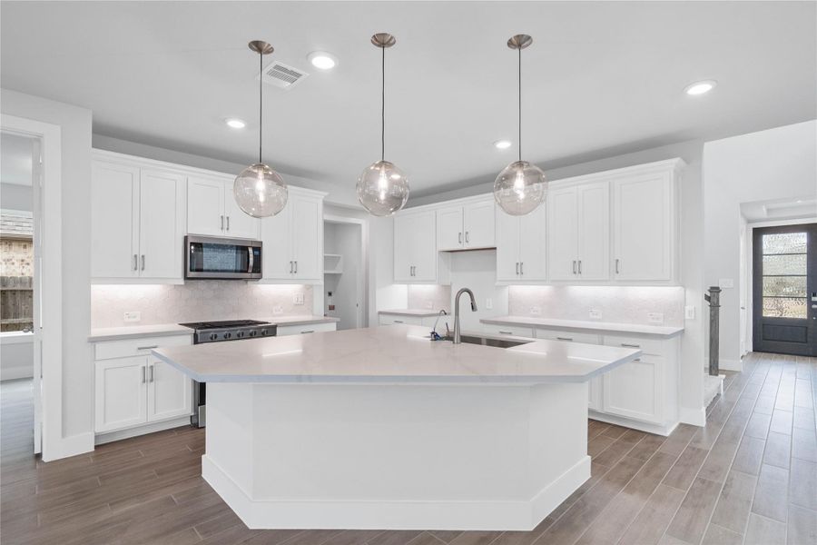 The stunning and generously sized center island features a breakfast bar, perfect for casual dining and entertaining. The island is beautifully designed with pristine quartz countertop and elegant pendant lights.