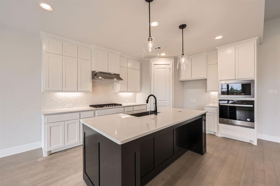 Kitchen featuring oven, gas cooktop, under cabinet range hood, a sink, and built in microwave Kitchen featuring oven, gas cooktop, under cabinet range hood, a sink, and built in microwave
