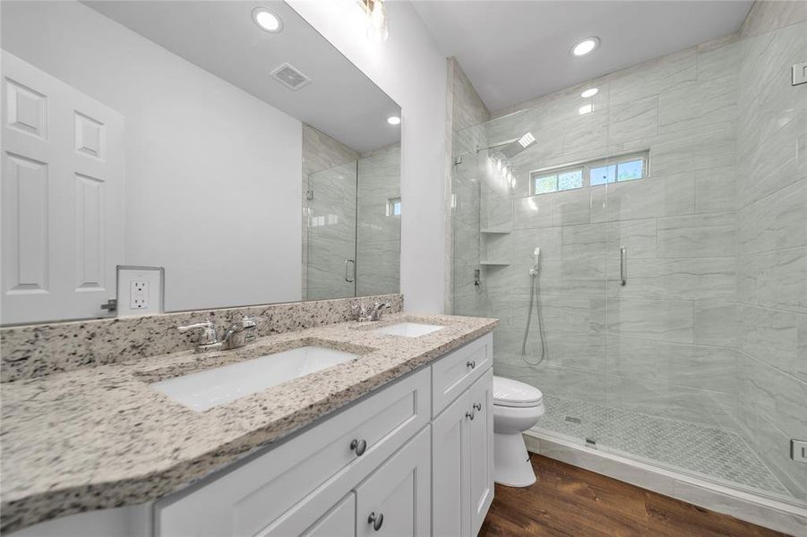 Bathroom featuring visible vents, a sink, a stall shower, and wood finished floors