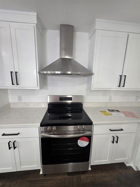 Kitchen featuring electric stove, wall chimney exhaust hood, and white cabinets Kitchen featuring electric stove, wall chimney exhaust hood, and white cabinets