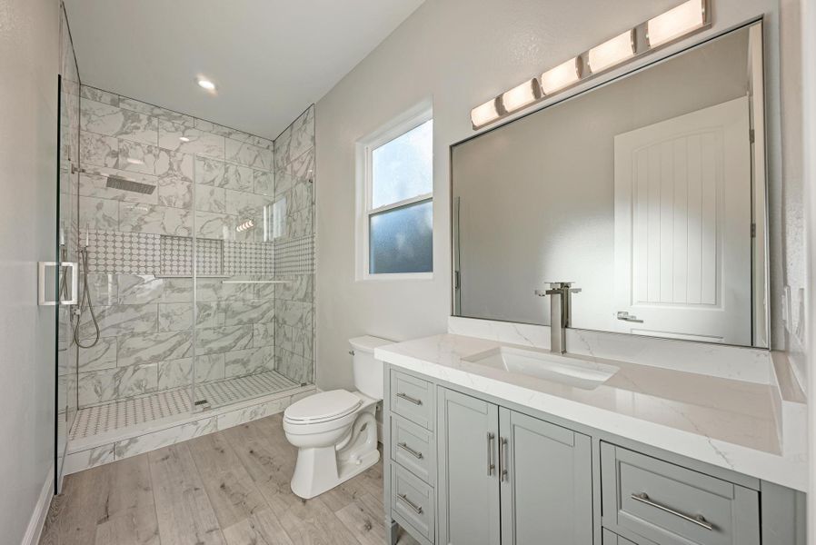 Bathroom featuring vanity, a shower stall, light wood finished floors, and recessed lighting