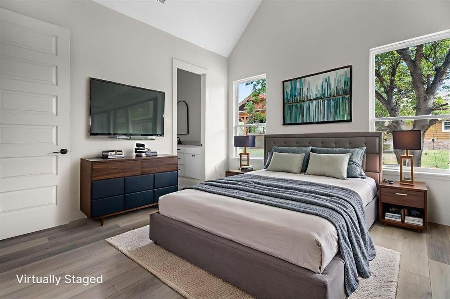 Bedroom featuring ensuite bathroom, high vaulted ceiling, and wood finished floors