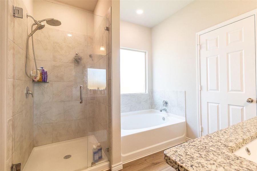 A tranquil primary bath featuring a spacious shower and a relaxing soaking tub with abundant natural light.