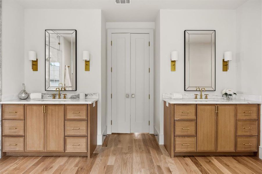 Dual vanities featuring wood cabinetry, marble countertops, and undermount sinks with brass fixtures Dual vanities featuring wood cabinetry, marble countertops, and undermount sinks with brass fixtures