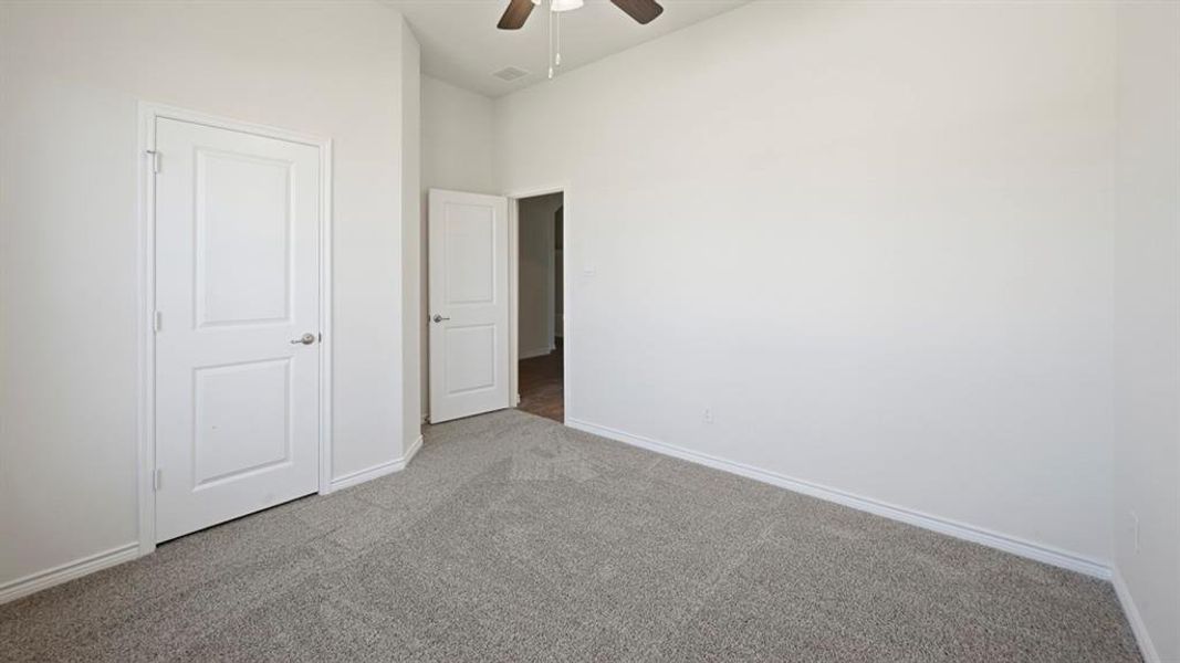 Spacious room with gray textured carpeting and crisp white baseboards