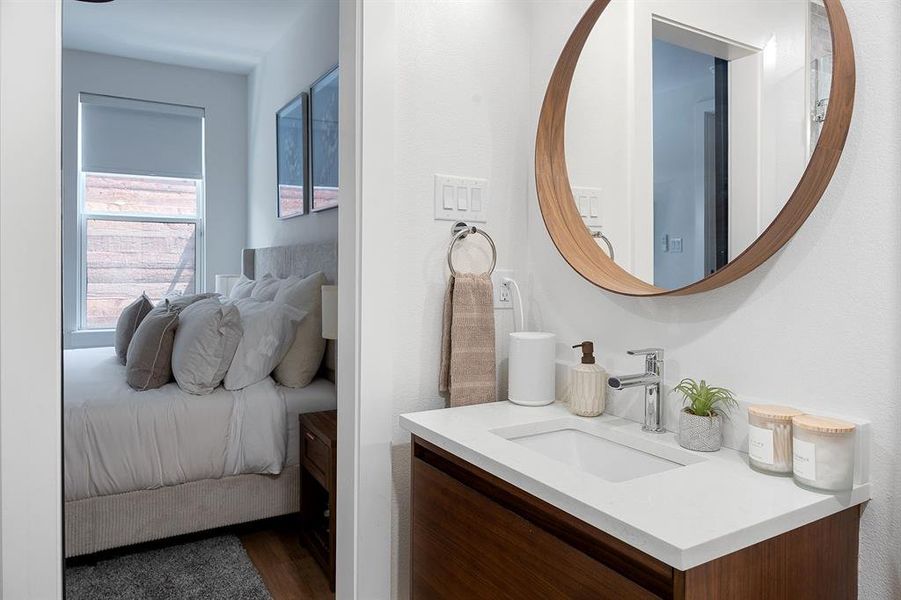 Bathroom vanity featuring a vessel sink, chrome faucet, and a round wood-frame mirror