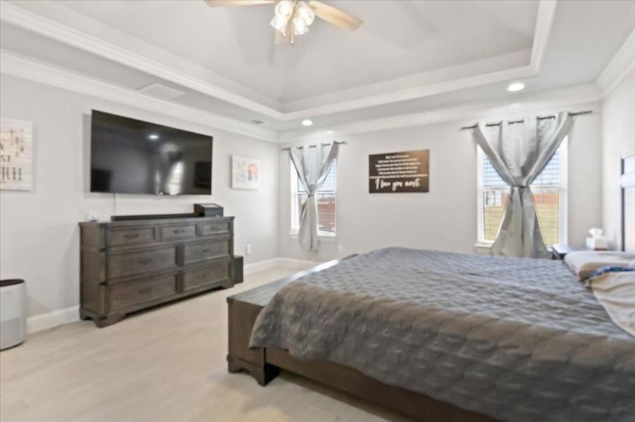 Bedroom featuring light wood finished floors, baseboards, a tray ceiling, and recessed lighting