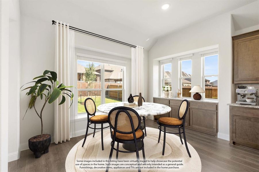 Bright breakfast nook with round marble table, rattan chairs, vaulted ceiling, and large windows overlooking backyard Bright breakfast nook with round marble table, rattan chairs, vaulted ceiling, and large windows overlooking backyard