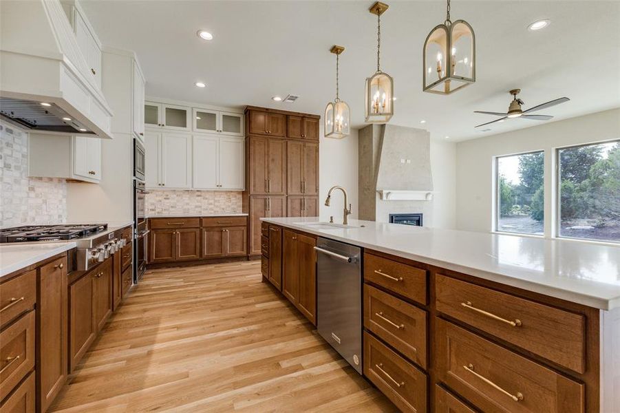 Kitchen with stainless steel appliances, a sink, premium range hood, white cabinets, and brown cabinets