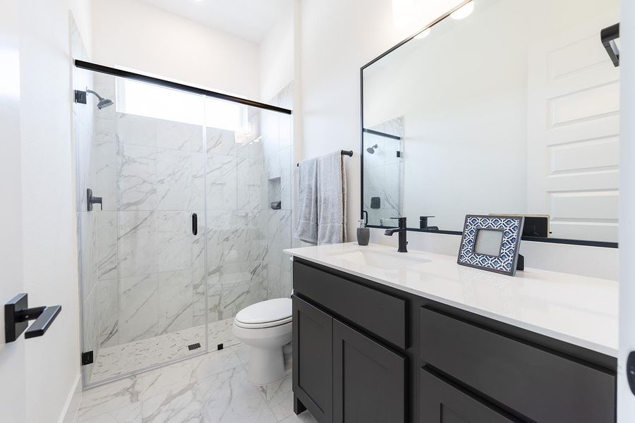 Guest Bathroom with modern finish out featuring marbled tile finish in oversized showers.  Glass doors with black accents.