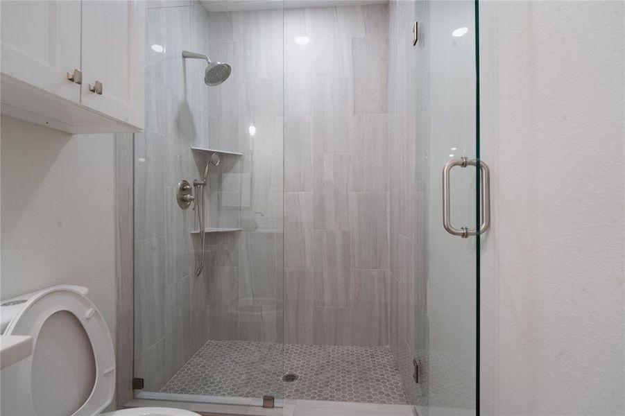 Bathroom with a shower stall and toilet