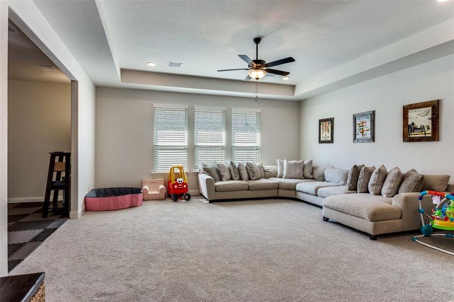 Living area featuring a tray ceiling, carpet flooring, and ceiling fan Living area featuring a tray ceiling, carpet flooring, and ceiling fan