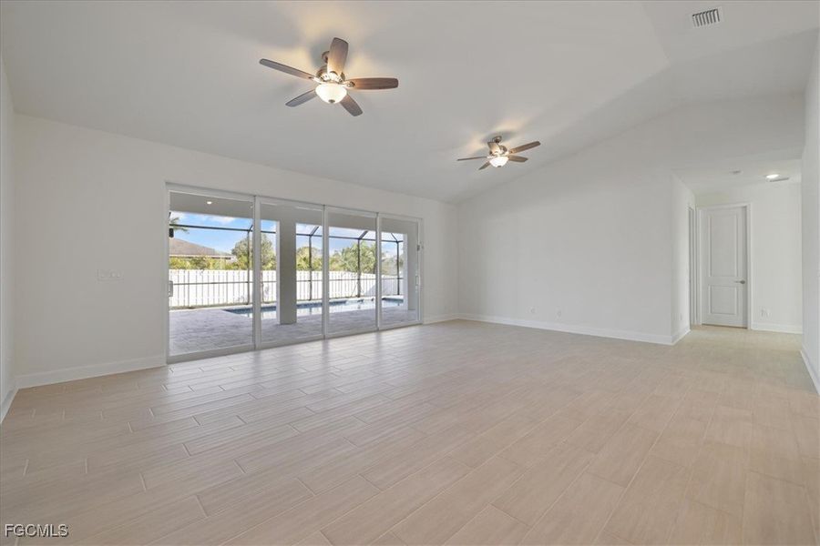 Empty room with lofted ceiling, wood tiled floors, and a ceiling fan Empty room with lofted ceiling, wood tiled floors, and a ceiling fan