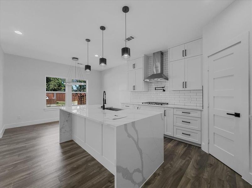 Kitchen with decorative backsplash, white cabinets, light stone counters, hanging light fixtures, and recessed lighting Kitchen with decorative backsplash, white cabinets, light stone counters, hanging light fixtures, and recessed lighting