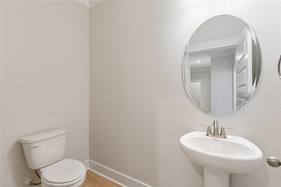 A pristine powder room featuring a classic pedesta