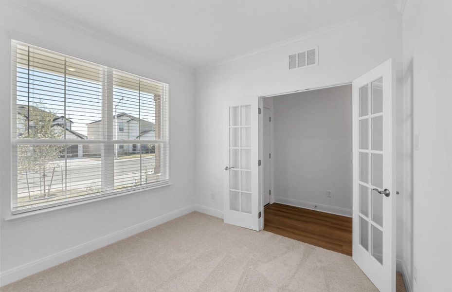 Unfurnished room featuring french doors, ornamental molding, and light colored carpet