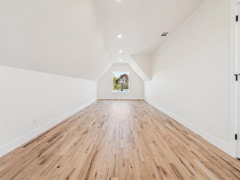 Bonus room with light hardwood / wood-style floors and lofted ceiling