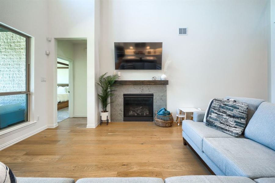 Living room with a towering ceiling, a tile fireplace, and hardwood / wood-style floors