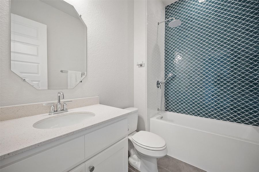 Bathroom with a textured wall, shower / tub combination, and vanity