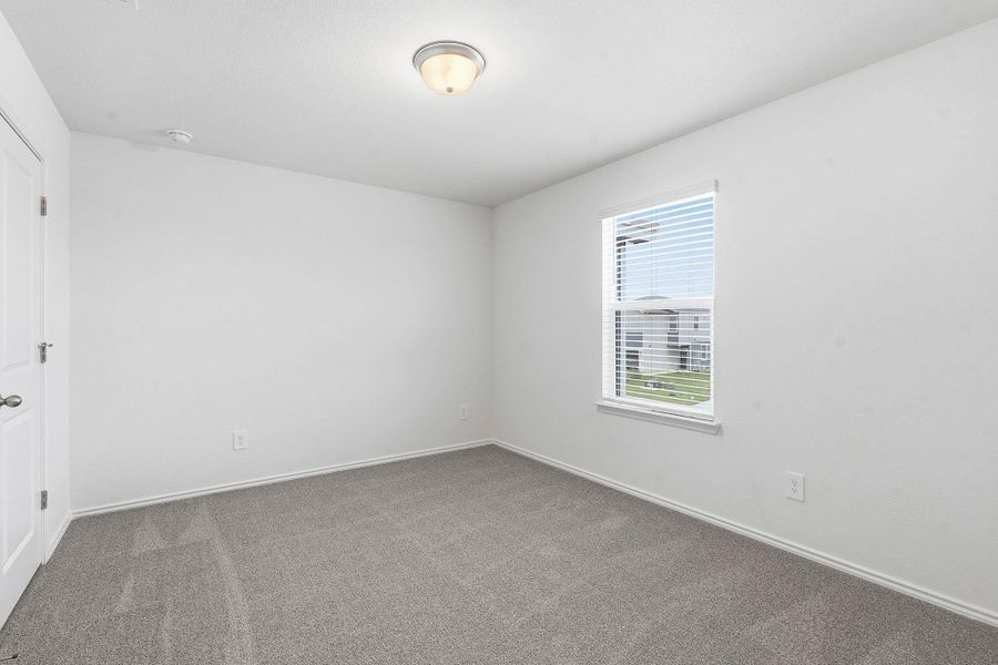 Carpeted room with a single window featuring white blinds, a white door with a round knob, and a ceiling-mounted light fixture Carpeted room with a single window featuring white blinds, a white door with a round knob, and a ceiling-mounted light fixture