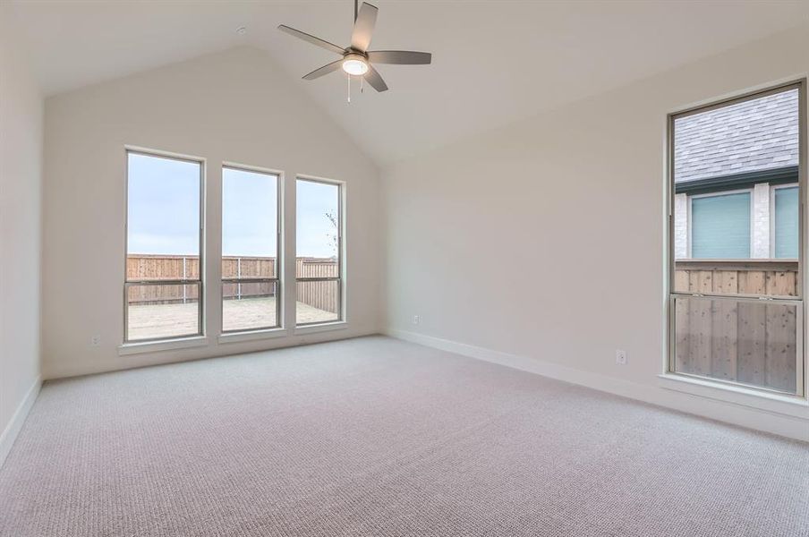 Carpeted empty room with ceiling fan and high vaulted ceiling