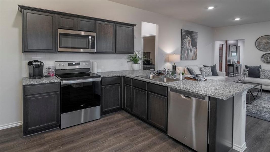 Kitchen with open floor plan, stainless steel appliances, a peninsula, dark wood-style floors, and recessed lighting