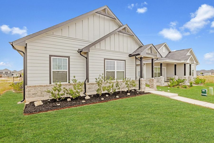 View of front of property featuring a front yard, covered porch, and board and batten siding
