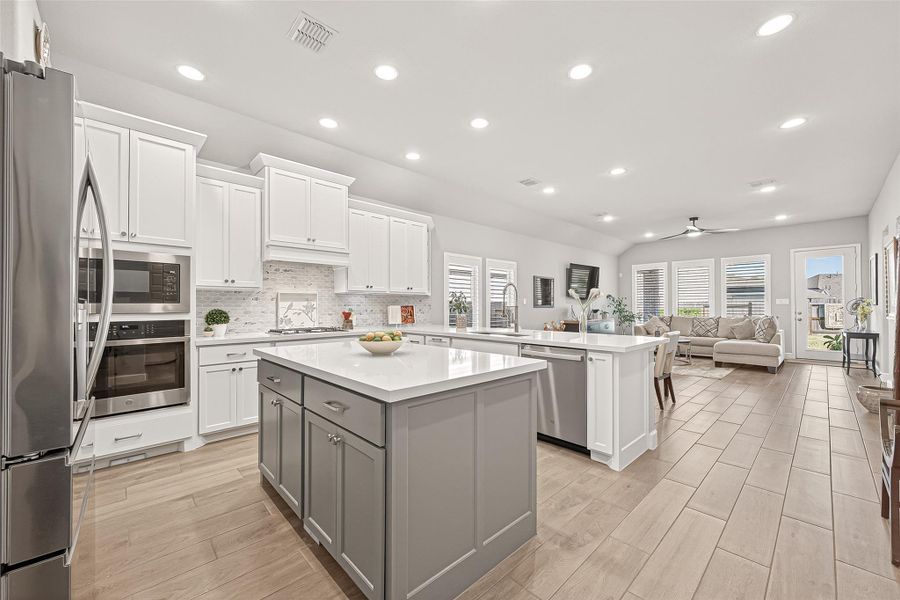 Open-concept kitchen flows into dining and living areas, creating an inviting, light-filled space perfect for entertaining. (Note: Photo is staged; property is currently vacant.) Open-concept kitchen flows into dining and living areas, creating an inviting, light-filled space perfect for entertaining. (Note: Photo is staged; property is currently vacant.)