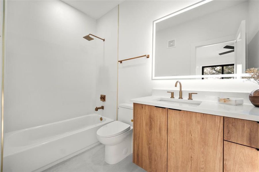 Full bathroom featuring washtub / shower combination, toilet, vanity, and tile patterned flooring