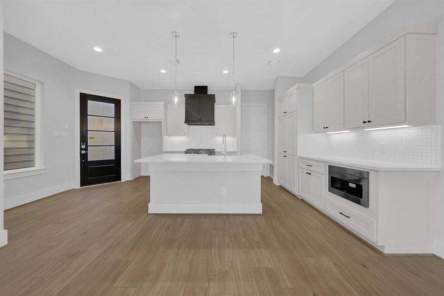 Sharp Microwave Drawer with hidden control top is seamlessly integrated below the countertop, blending perfectly with the cabinetry, maintaining the kitchen's streamlined and contemporary aesthetic.Stylish kitchen with white shaker-style cabinets.